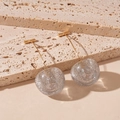 Détail de boucles d'oreilles cerises transparentes avec paillettes sur travertin beige - Blanc-Pomme