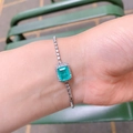 Primer plano de una pulsera plateada con circón verde rectangular en la muñeca de mujer - Pulsera Azul Paraiba [16cm+5cm de extensión]