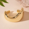 Detailed macro view of gold wave-shaped irregular cuff bracelet with high-polish metallic finish - Gold