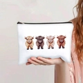Handheld view showing four cartoon highland cows printed on a white canvas makeup pouch - Highland Cow Group Cartoon Style (141-3)