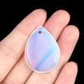 Blue and white teardrop crystal pendant held on finger for size reference - Opalite (Synthetic)