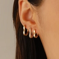Primo piano di orecchini a cuore dorati e un ear cuff a U con strass sull'orecchio - Orecchini a Cuore Pavé di Strass Oro (11471)