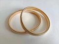 Detail of two gold spring sleeve garters on white background with metallic texture - Gold