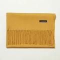 Close-up detail of soft yellow cashmere scarf with elegant fringe texture and label - 70cm / Turmeric