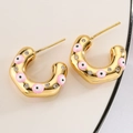 Makro-Detail goldener C-förmiger Creolen mit rosa Evil Eye Emaille und Zirkoniasteinen - Rosa
