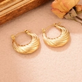 Gros plan de boucles d'oreilles dorées torsadées en U sur un fond esthétique vintage - Fermoir Texturé en Spirale (WGXA0035055010C)