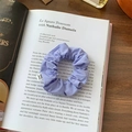 Detail of purple fabric scrunchie with From Sheep label on an open vintage book - Purple