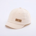Détail du bonnet bébé en coton beige montrant l'écusson en cuir fait main avec ours - 48cm (6-18 Mois) / Beige