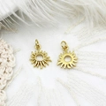 Detailed close-up of two mini golden sun pendants with hanging rings on lace and feathers - Sun