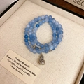 Macro detail of multilayer blue bead bracelet featuring a silver money bag charm with engraving - Aquamarine Color (Lucky Bag)
