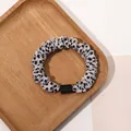 Close-up of grey polka dot scrunchie with black acrylic detail on a wooden tray - Satin Polka Dot White