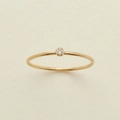 Anello dorato minimalista con pietra portafortuna rotonda su superficie beige - US 7 / Aprile (Zircone Chiaro)