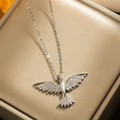 Collier avec pendentif phénix en argent et zircone sur un coffret à bijoux en velours beige - Argenté
