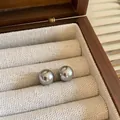 Close-up of grey pearl stud earrings presented in a luxury wooden jewelry display box - 8mm / Gray