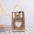 Close-up of a beige knitted crossbody bag with white heart pattern on checkered cloth - Brown