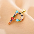 Close-up of letter P pendant with multi-color zircon stones on pink silk background - Letter P