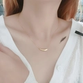 Elegant gold curved tube pendant necklace worn by a model on a white knit sweater - Gold Minimalist Pendant