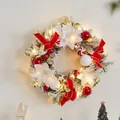 Christmas wreath with red bows, white flowers, and warm LED lights on a white wall - Red White Flower Wreath 40cm With Lights