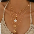 Gold multi-layer necklace with starfish, shell, pearl and flower charms on a model - Gold 4-Pendants