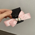 Dettaglio del fermaglio per capelli a fiocco in raso rosa con perle su carta - Rosa
