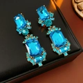 Detailed close-up of vintage gold earrings with large blue crystals on black leather - Silver Earring Post-Blue