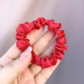 Macro shot of red satin scrunchie showing glossy silk-like texture and soft elastic pleats - Red