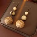 Detalle de pendientes bohemios vintage con cuentas de madera natural en un joyero texturizado - Gancho de oreja-Café