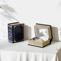 Dark blue book-shaped jewelry box with gold patterns and white satin ring slots - Plastic / Deluxe Court Blue