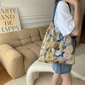 Detailed close-up of a floral oil painting canvas tote bag with shoulder straps and label - Monet Garden Blue Yellow
