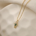 Detail of a gold boy pendant necklace with a green rectangular stone on beige fabric - May Green (Emerald Color)