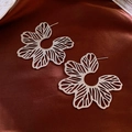 Close-up of silver hollow floral earrings on a dark red silk textured background - 50# Silver Hollow Radial Flower (925 Sterling Silver Earring Post)