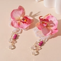 Detalle de pendientes de flores rosas con perlas y borlas de cristal sobre fondo cálido - Flor Rosa (Aguja de Plata)