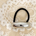 Close-up of polished silver metal buckle and black elastic hair tie on white lace fabric - Silver Bar