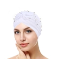 Close-up of pleated white turban hat featuring elegant faux pearls on a professional model - White