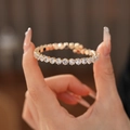 Gedetailleerde close-up van een fonkelende vergulde tennisarmband met witte zirkonia's - Goud