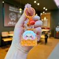 Handheld view of orange acrylic liquid keychain with star glitter and cartoon charm - Orange Night Light Bubble Beads