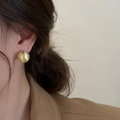 Orecchino a sfera dorato spazzolato con finitura opaca vintage su una modella - 14mm / Oro