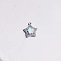 Macro detail of star-shaped silver pendant with sparkling crystals and iridescent stone - White