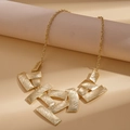 Détail du collier géométrique doré avec finition en métal brossé sur supports sobres - Doré