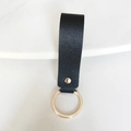 Gros plan du porte-clés en similicuir noir avec anneau et rivet dorés sur fond blanc - Noir