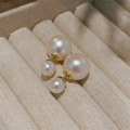 Detailopname van dubbele pareloorbellen met goudlaagje op een beige fluwelen juwelendoosje - Kleurrijk wit