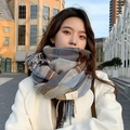 Blue brown and beige plaid scarf with fringes worn by model in a street setting - New Blue