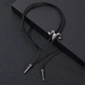 Close-up of vintage silver ram skull bolo tie with black braided cord on dark surface - One Size / Antique Silver Argali Skull