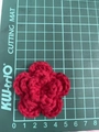 Macro view of 7cm handmade red crochet flower measured on a green grid cutting mat - 5cm-5.5cm / Dark Red