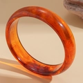 Detail of amber resin bangle showing elegant translucent texture and warm orange tones - Amber