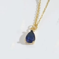 Makroaufnahme einer Goldkette mit birnenförmigem blauem Tropfenanhänger und Krappenfassung - Königsblau