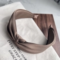 Detail of a brown twisted fabric headband resting on a stylish decorative beige cloth bag - Brown