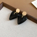 Detail shot of heart-shaped black acrylic earrings with gold beads on grey textured cloth - 925 Silver Pin Earrings / Black
