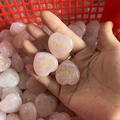 Hand holding three heart-shaped pink quartz stones engraved with golden Peace text - Peace