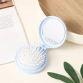 Light blue foldable round pocket hairbrush with mirror on a wooden tray with green leaves - Light Blue